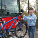 man putting his bicycle on the fixed route bus racks