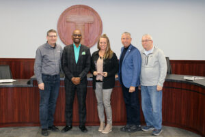 Photo of Sauk Rapids Mayor Kurt Hunstiger, Metro Bus CEO Ryan I. Daniel, Metro Bus CAO Sunny Hesse, St. Cloud Mayor Dave Kleis and Board Member John Libert standing in the Metro Bus Board Room to recognize Ms. Hesse as recipient of the 2023 MPELRA Excellence in Labor Relations Award.