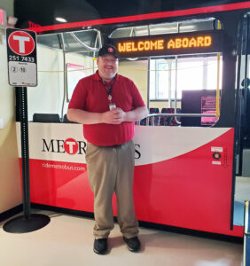 Community Outreach & Mobility Specialist Nick standing by the bus shell in the Mobility Training Center