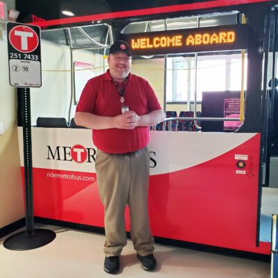 Community Outreach & Mobility Specialist Nick standing by the bus shell in the Mobility Training Center
