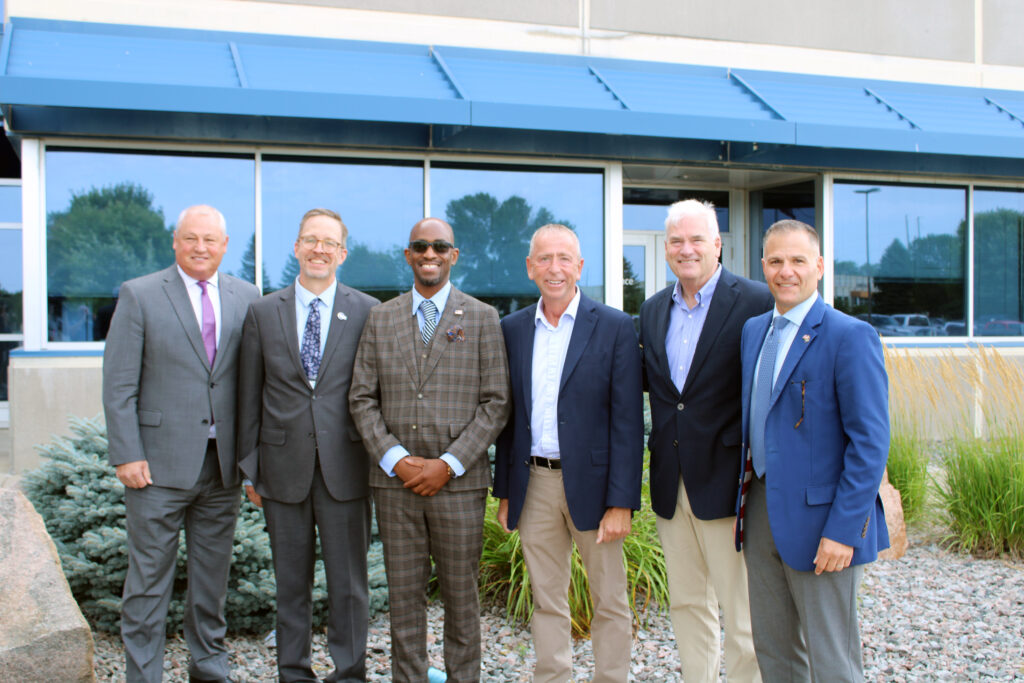 New Flyer CEO Paul Soubry, CTAA Executive Director Scott Bogren, Metro Bus CEO Ryan I. Daniel, Metro Bus Board of Commissioners Chair Dave Kleis, Congressman Tom Emmer, FTA Administrator Marc Molinaro in front of the St. Cloud New Flyer facility August 14, 2025