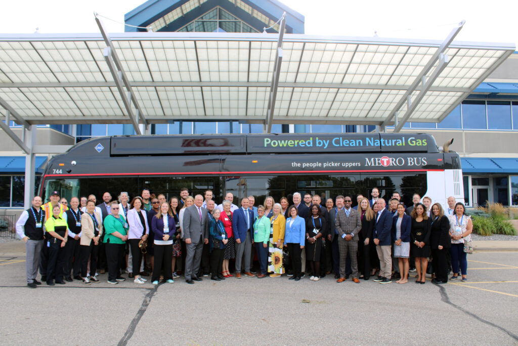 Group of people standing in front of a Metro Bus parked in front of the New Flyer facility.