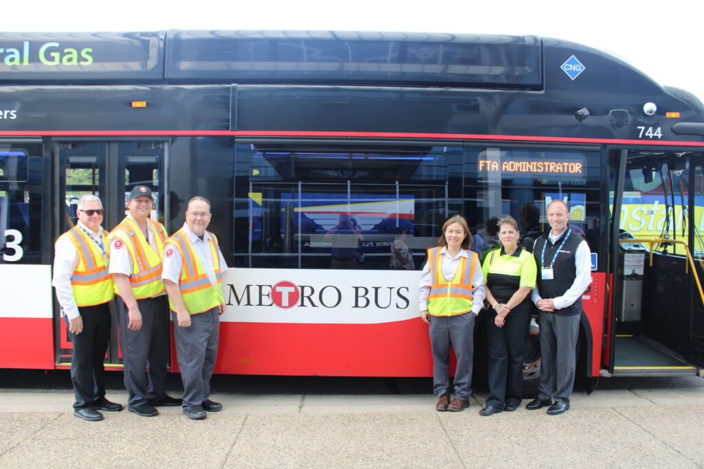 6 Metro Bus Employees smiling in front of a Metro Bus.