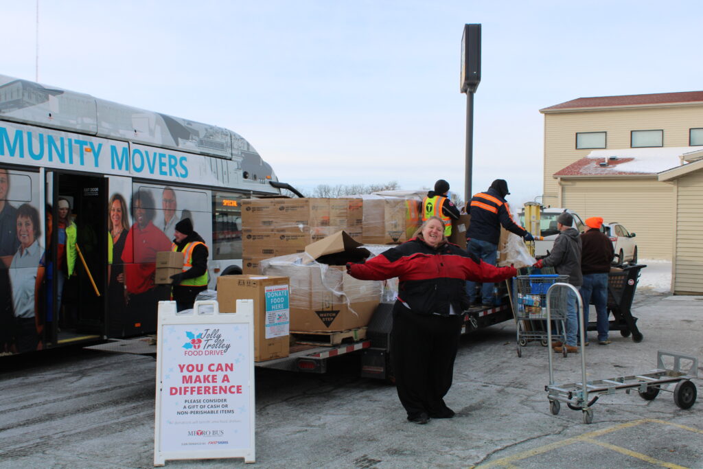 A group of people unload boxes of food from a trailer.